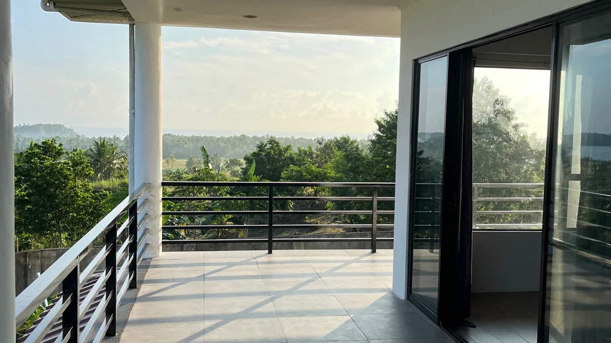 Terrace of HelloWorld Siargao Homestay with a view over the trees to the sea